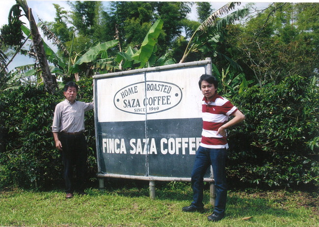 サザ農園の看板に立つ 鈴木 誉志男（写真左）、鈴木太郎（写真右）
