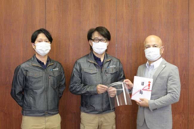 和泉足利市長（写真右）に現物を紹介する弊社社長の森西（写真中央）と、製作責任者の井本（写真左）
