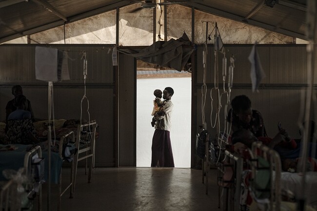南スーダン、ベンティウにあるMSFの病院で妹を抱く女性。女性は肺炎と高熱を患っていたが順調に回復している　(C)Sean Sutton