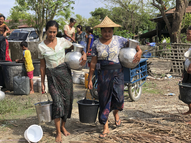 ミャンマー西部ラカイン州でバケツいっぱいの水を運ぶ女性たち。毎年乾季に問題になる水不足は、多くの住民の悩みの種になっている　(C)ICRC
