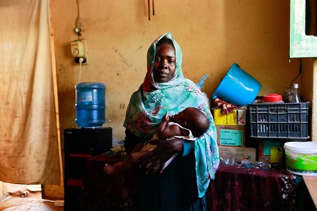 ハルツームから逃れ、ワドメダニの避難所で生まれたばかりの子どもを抱く女性＝2023年12月10日 (C) Fais Abubakr