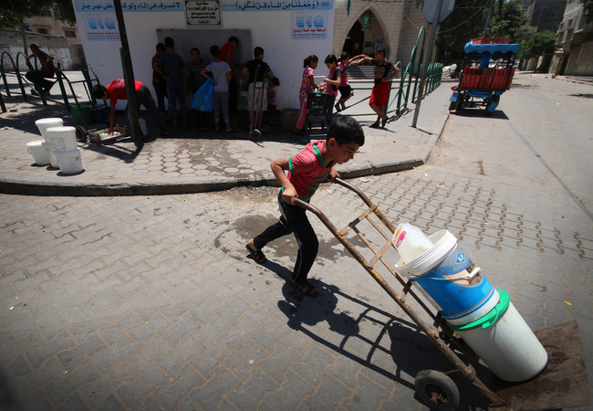 5時間の一時停戦中に汲んだ飲み水を自宅に運ぶ少年 ©Jozef Nateel / Save the Children