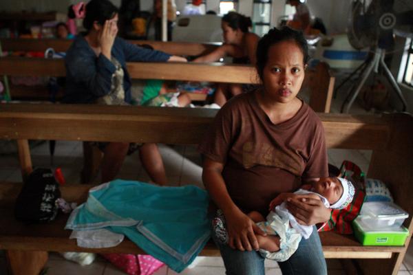 © UNICEF Philippines/2013/JMaitem　タクロバンの教会に家族とともに避難している母親と幼い子ども