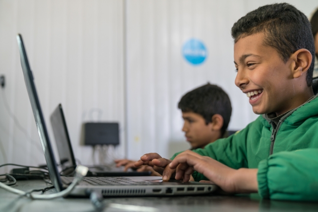 ヨルダンのザータリ難民キャンプにあるユニセフの学習支援センターで、ノートパソコンを使うシリア難民の男の子（11歳）。(c)UNICEF_UN051294_Herwig