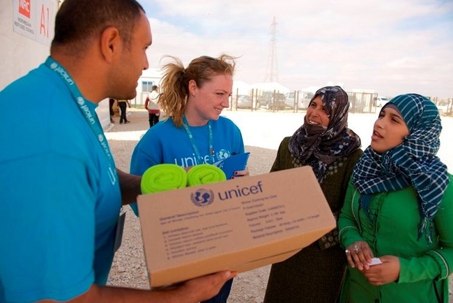 © UNICEF/Jordan-2013/Noorani　　ヨルダンのザータリ難民キャンプに支援物資の冬の衣類キットを届けるユニセフ職員。