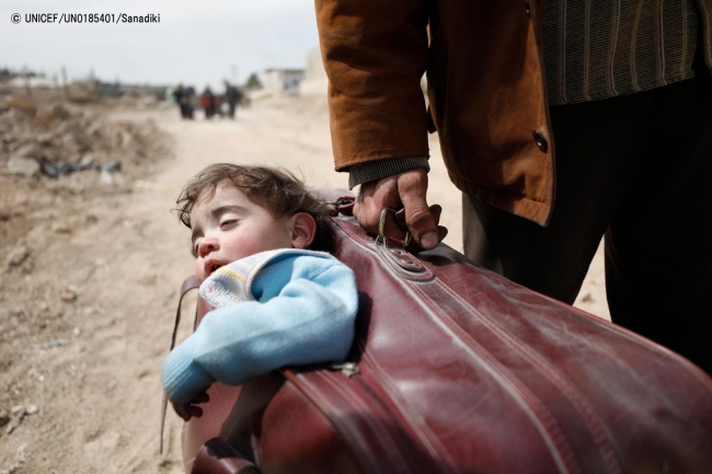 スーツケースで子どもを運び、避難する男性。(2018年3月15日撮影) (C) UNICEF_UN0185401_Sanadiki