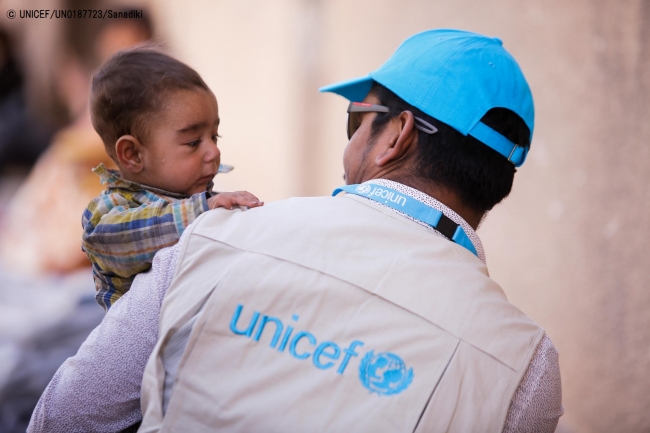 ユニセフの子どもの保護専門官に抱かれる生後6カ月のユスフ君。(2018年3月20日撮影) © UNICEF_UN0187723_Sanadiki