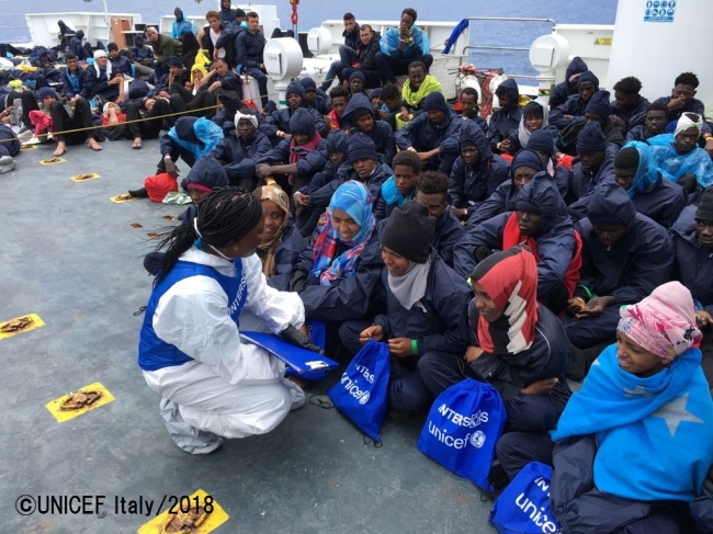 イタリア沿岸警備船に乗船している子どもたちを保護し、支援物資を配布するユニセフのパートナー団体の職員。スペインは、人道原則と国際法に準じ、このような極めて弱い立場にある子どもたちや妊婦を受け入れた。©UNICEF Italy_2018