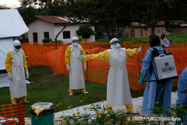 エボラ治療センターで働く医療従事者たち。エボラ患者に接触した後、感染予防のために念入りに消毒をしている。© UNICEF_UN0235950_Nybo