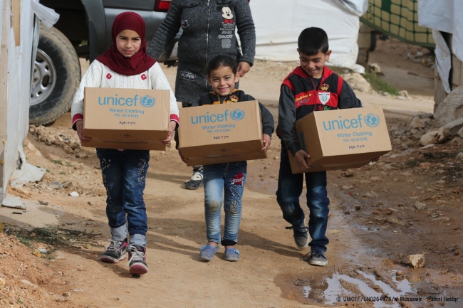 レバノン国内シリア国境近くの難民キャンプで、冬服などの支援物資を受け取った子どもたち。© UNICEF_UN0264878_al Mussawir - Ramzi Haidar