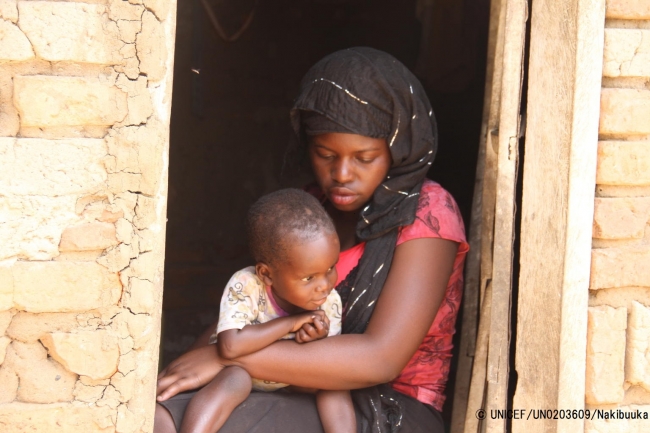 2歳の赤ちゃんを抱く母親のミリアさん。12歳で結婚を強いられ、妊娠したため、学校もやめなければならなかった。（ウガンダ）