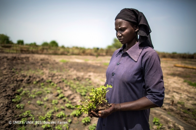 トマトの苗を手にする、5人の子をもつ母親のエリザベスさん。以前は広い農地で農作物を作っていたが、南スーダンでの紛争の影響で土地を失った。© UNICEF_UN067923_Gonzalez Farran