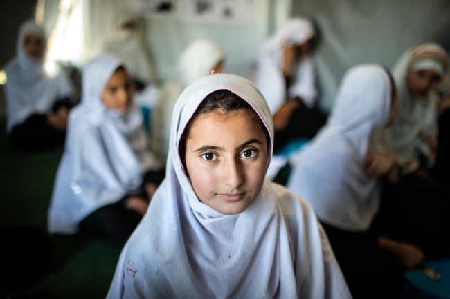 教室の机に座り、穏やかに微笑む12歳の女の子。2年前、戦闘地域の村から家族とともに避難してきた。村に住んでいたころは教育を受けることができなかったという。© UNICEF_UN0309029_Kokic