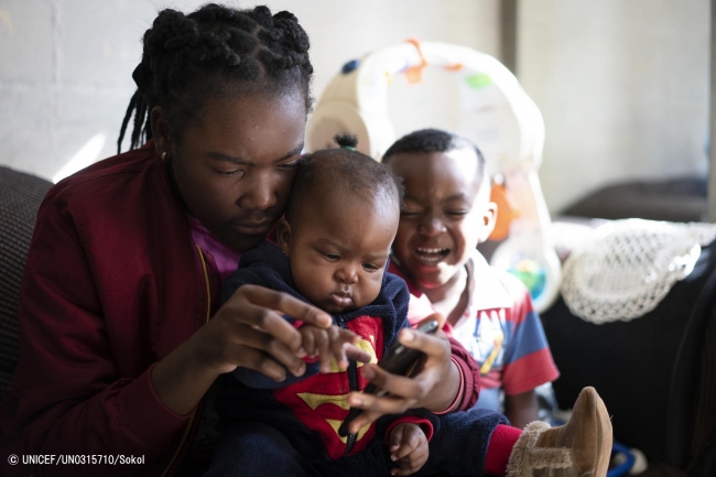 生後7カ月の妹と4歳の弟の面倒を見る南アフリカの少年。(2019年5月撮影) © UNICEF_UN0315710_Sokol