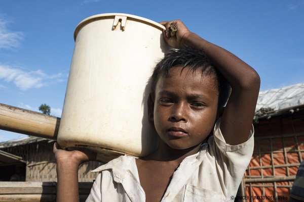 バングラデシュのクトゥパロン難民キャンプで、週に2回バケツに入れたほうれん草を売りに行く8歳のイドルスくん。(2019年6月撮影) © UNICEF_UN0331066_Nybo