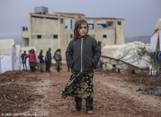 シリア北西部トルコ国境近くの村に設置された非公式居住区で、テントの外に立つ女の子。(2019年12月30日撮影) © UNICEF_UNI275751_Akacha