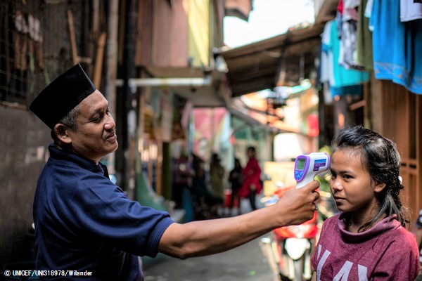 ジャカルタの低所得者層が多く住む地域で、赤外線体温計を使って体温を測ってもらうザハラさん。(インドネシア、2020年4月1日撮影) © UNICEF_UNI318978_Wilander