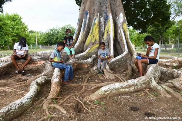 ソーシャルディスタンスを保ちながら、木の下でインターネットを利用する子どもたち。(ジャマイカ、2020年9月撮影) © UNICEF_UN0352054_Makyn
