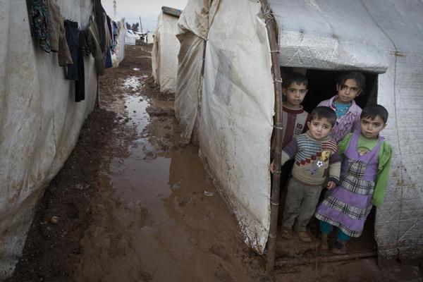 シリア北部、トルコ国境沿いに設置されたバブ・アル・サラマ国内避難民キャンプにて、避難用テントの外に立つ子どもたち。2014年1月撮影。© UNICEF/NYHQ2014-0003/Diffidenti