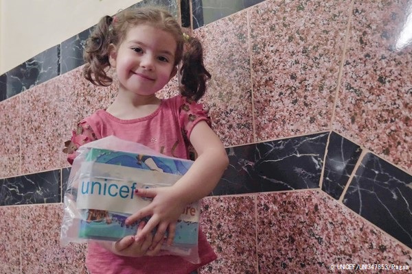 首都カイロで、移民の子どもと家族に配布しているCOVID-19衛生キットや本を受け取った女の子。(エジプト、2020年6月撮影) © UNICEF_UNI347853_Ragaa