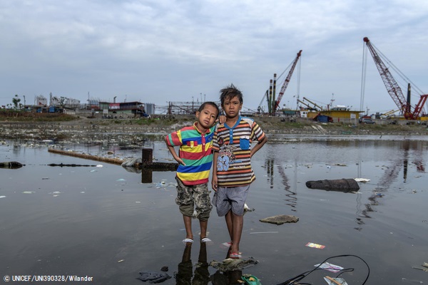 北ジャカルタで増水になった自宅近くの外に立つ7歳のサトリオくん(左)と9歳のアフメドくん(右)。(インドネシア、2020年9月撮影) © UNICEF_ UNI390328_Wilander