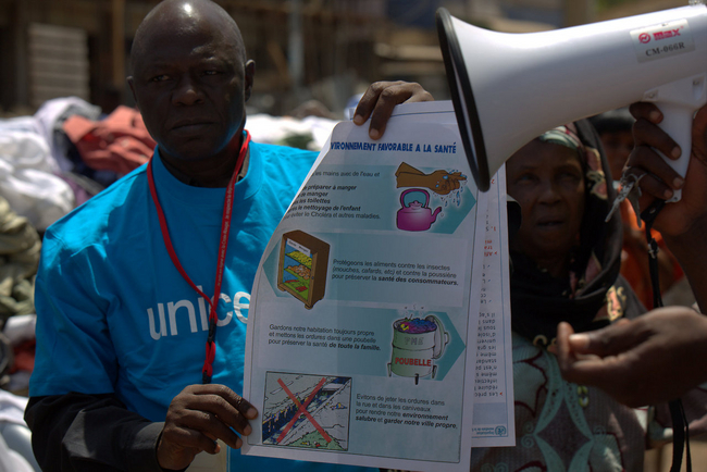 ユニセフは コナクリでエボラの発症を防ぐ ため、啓発活動を実施。ポス ターで予防 方法を伝えるスタッフ。©UNICEF/Guinea