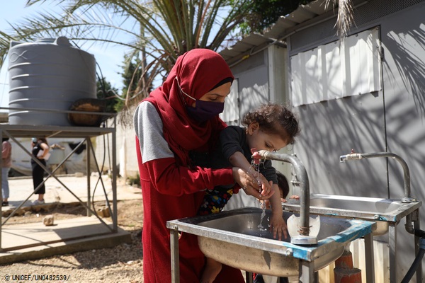 母親に抱かれながら手を洗う1歳のファティマちゃん。(2021年5月撮影) (C) UNICEF_UN0482539_