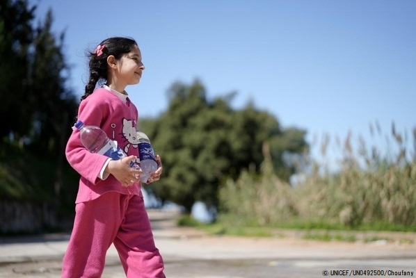 水の入ったペットボトルを持って歩く10歳のシリンさん。家族のために、毎日父親と一緒に水を汲んで自宅まで運んでいる。(2021年3月撮影) © UNICEF_UN0492500_houfany