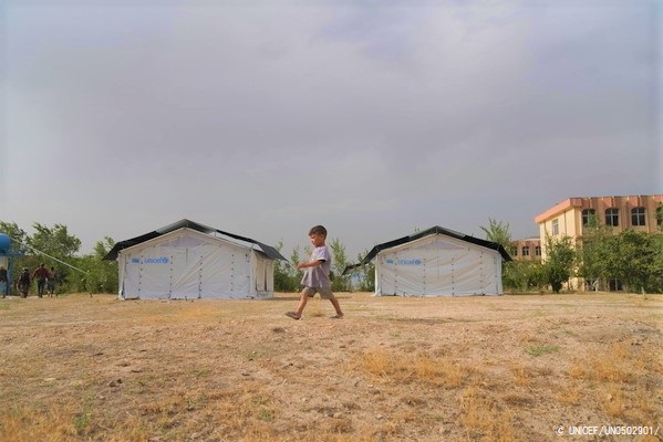 クンドゥズ州、サーレポル州、タカ―ル州から避難してきた400世帯以上の家族が生活するカブール市内の高校で、ユニセフが設置しているテントのそばを歩く子ども。(2021年8月撮影)※本文との直接の関係はありません © UNICEF_UN0502901_