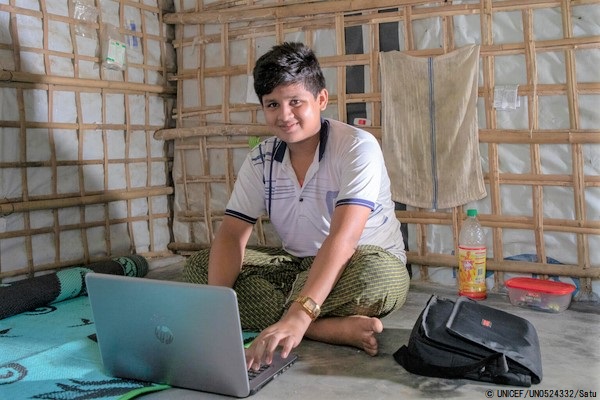 コックスバザールの難民キャンプの自宅で、パソコンを使ってコンピューターと英会話の授業を受ける15歳のロヒンギャ難民のムハマドくん。(バングラデシュ、2021年9月撮影) © UNICEF_UN0524332_Satu