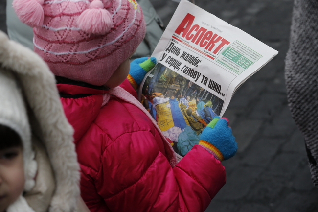 デモ参加者数人が死亡したと報じる新聞を読む子ども。©UNICEF/UKRAINE/2014/V.Musienko