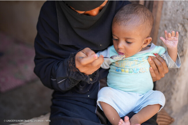 ラヒジュ県にある自宅で、母親にご飯を食べさせてもらう生後7カ月のサナドちゃん。重度の急性栄養不良のため2カ月間治療を受け、今は回復傾向にある。(イエメン、2023年5月撮影) (C) UNICEF_UN0852949_Alaa Noman - YPN