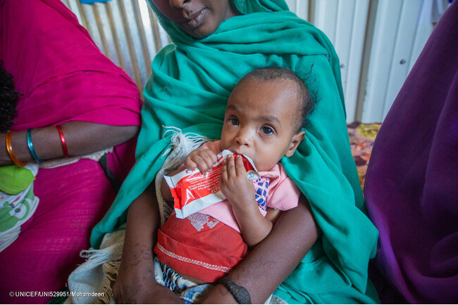 カッサラ州の保健施設で重度の栄養不良と診断され、すぐに食べられる栄養治療食を口にする2歳のアイーダちゃん。(スーダン、2024年2月29日撮影) (C) UNICEF_UNI529951_Mohamdeen