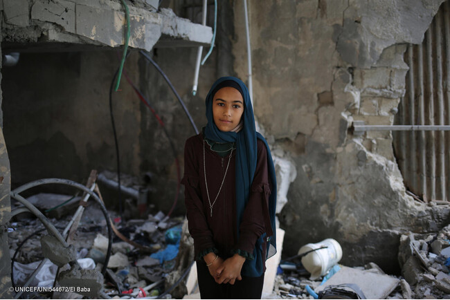 戦闘機によって破壊されたラファの自宅の中で立つ12歳のサマさん。「今すぐに戦争をやめてほしいです。何度も何度も避難したくないです」と話す。(ガザ地区、2024年3月撮影) (C) UNICEF_UNI544672_El Baba