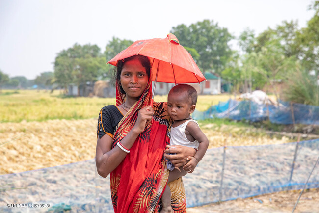 全国的な熱波に見舞われる中、日傘で対策する親子。(バングラデシュ、2024年5月17日撮影) (C) UNICEF_UNI579538_