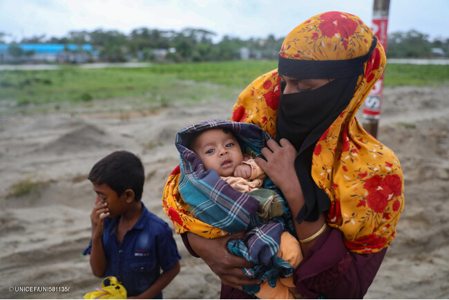 サイクロンが上陸する前に、最低限の荷物を持ち、雨の中、避難所へ向かう親子。(バングラデシュ、2024年5月26日撮影) (C) UNICEF_UNI581135_