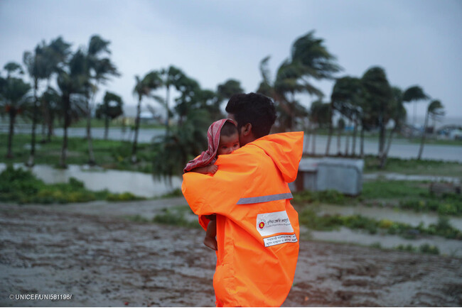 サイクロンが上陸する前に、雨の中を避難所へ向かう親子。(バングラデシュ、2024年5月26日撮影) (C) UNICEF_ UNI581196_