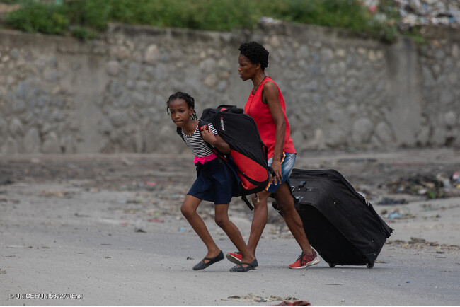 首都ポルトープランス中心部のSolino地区で起きた武装集団の襲撃後、家を捨てて逃げる親子。(ハイチ、2024年5月1日撮影) (C) UNICEF_UNI569270_Erol