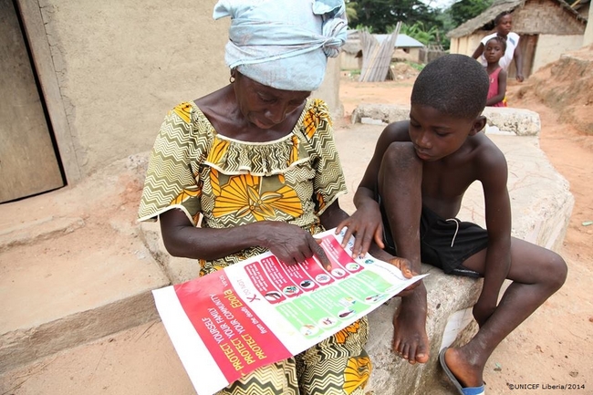 配布されたエボラの予防方法に関するちらしを読む住民。（リベリア）©UNICEF Liberia/2014