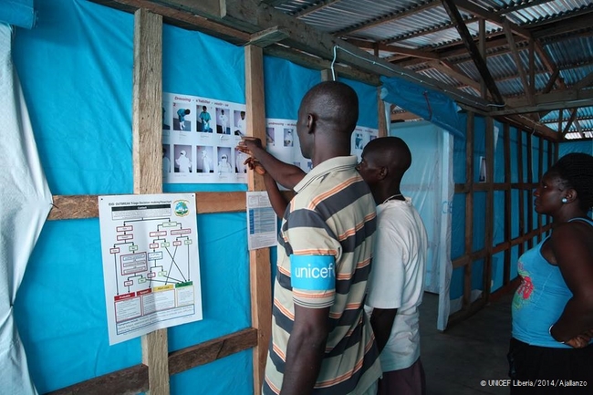 ポスターを見せながら、エボラ熱への正しい対処法を伝えるユニセフ職員。© UNICEF Liberia/2014/Ajallanzo