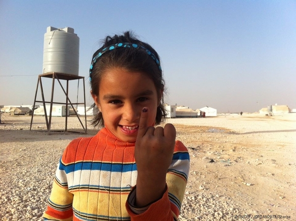 ポリオの予防接種を受けた子どもの指に着けられる紫色の印を見せる、ヨルダンに避難しているシリア難民の子ども。 ©UNICEF/JORDAN2013/Sharpe