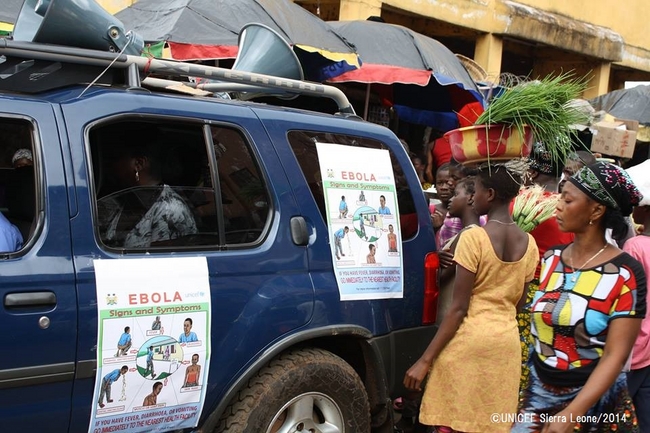 車に貼られたエボラに関するポスターを読む住民。©UNICEF Sierra Leone/2014