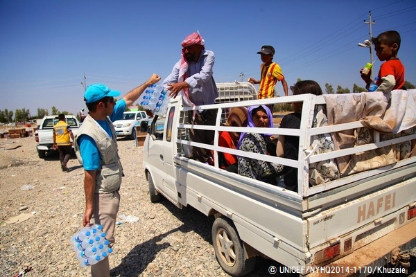 シリアの国境付近で、トラックで避難するヤズディ教徒の子どもや家族に水を配布するユニセフ・スタッフ。© UNICEF/NYHQ2014-1170/Khuzaie