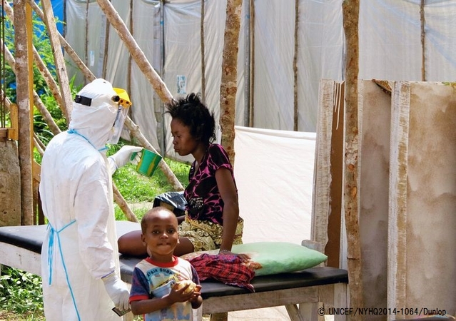 防護服を着てエボラ治療センターで患者に水を飲ませる保健員。© UNICEF/NYHQ2014-1064/Dunlop