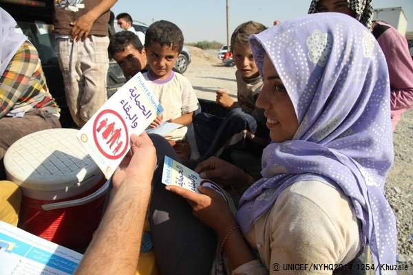 ユニセフが配布している保健や保護に関するチラシを受け取る女の子。© UNICEF/NYHQ2014-1254/Khuzaie