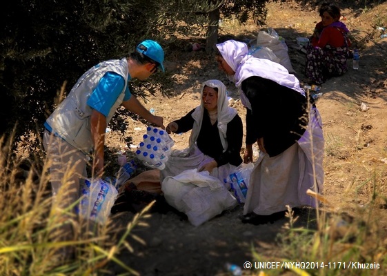シリアの国境まで逃れてきたヤズディ教徒の女性たちに水を提供するユニセフ・スタッフ。© UNICEF/NYHQ2014-1171/Khuzaie 