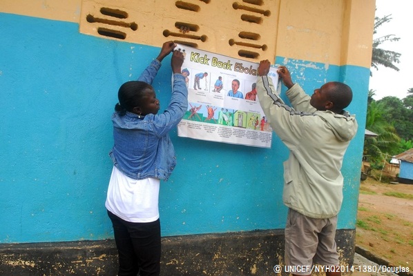 カイラフンで、エボラの症状や予防法が描かれたポスターを壁に貼るスタッフ。© UNICEF/NYHQ2014-1380/Douglas