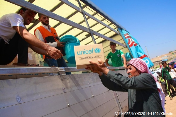 緊急支援物資の世帯向け・衛生用品の詰め合わせを受け取る男性。© UNICEF/NYHQ2014-1102/Khuzaie