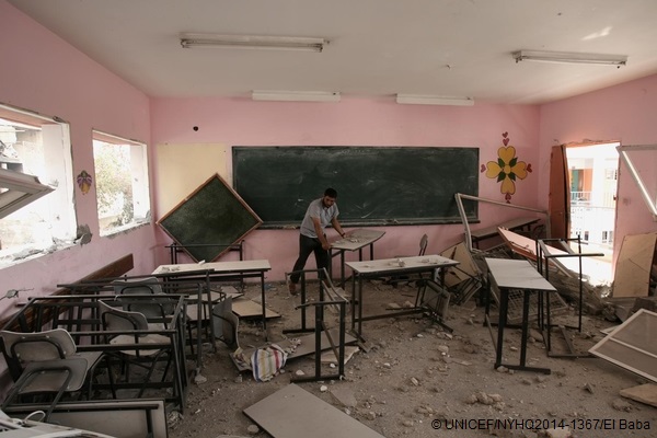 戦闘の被害を受けた教室の被害状況の調査や片づけを行う男性。© UNICEF/NYHQ2014-1367/El Baba
