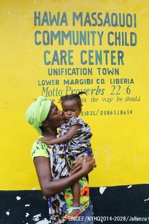 両親がエボラに感染して治療センターに搬送された後、兄弟と一緒に一時ケアセンターに連れてこられた1歳半の女の子とセンターのスタッフ。（リベリア）© UNICEF/NYHQ2014-2028/Jallanzo